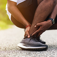 Person grasping their ankle | Neuropathy Treatments